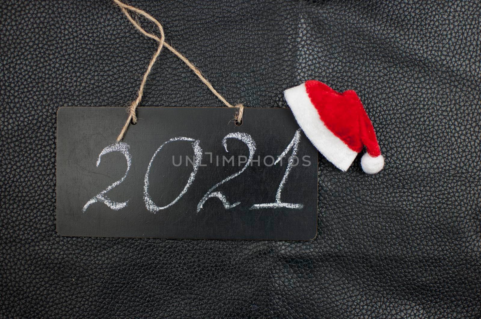 2021 - chalkboard with outlined text and Santa hat on black leather background