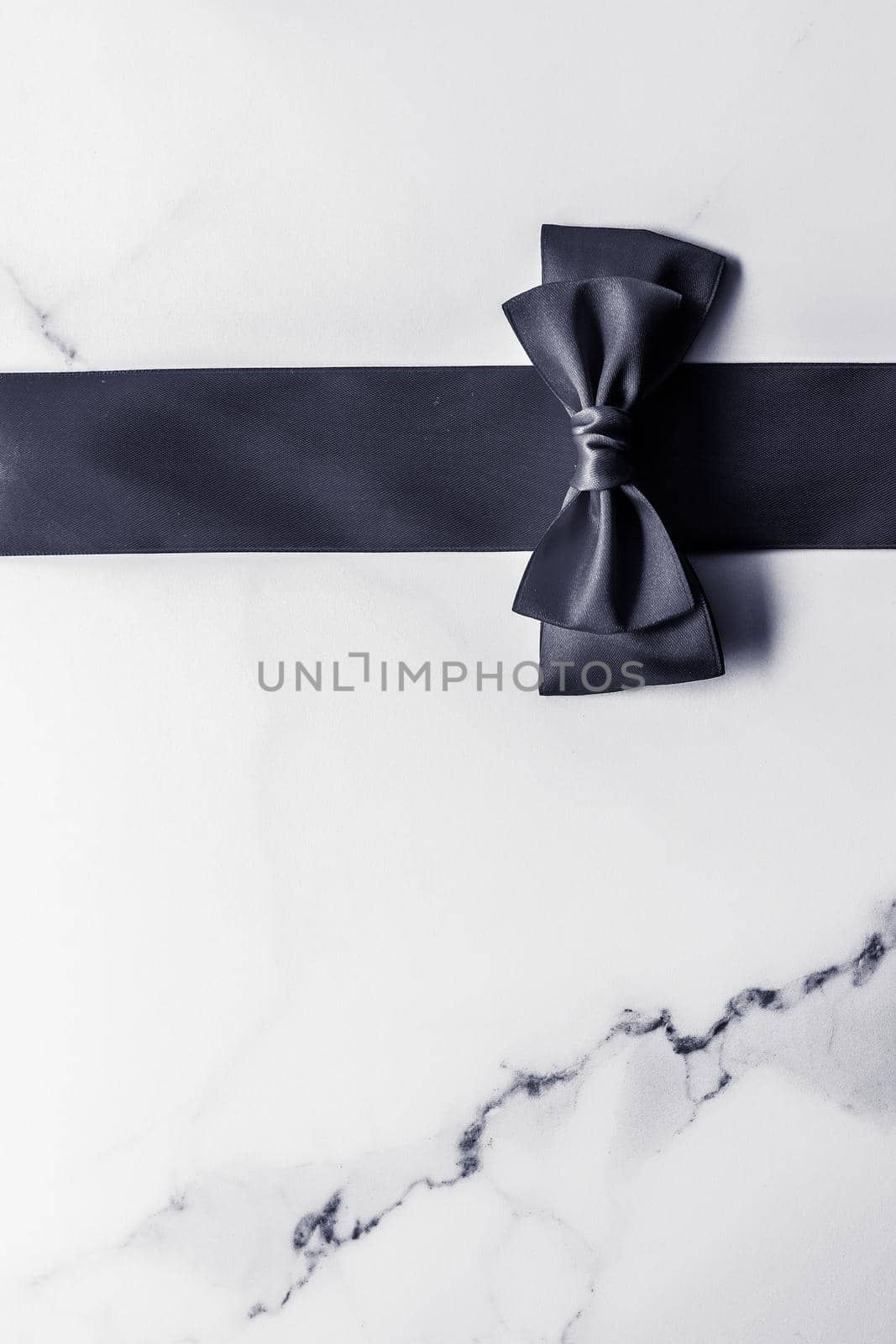 Holiday gift, decoration and sale promotion concept - Black silk ribbon and bow on marble background, flatlay