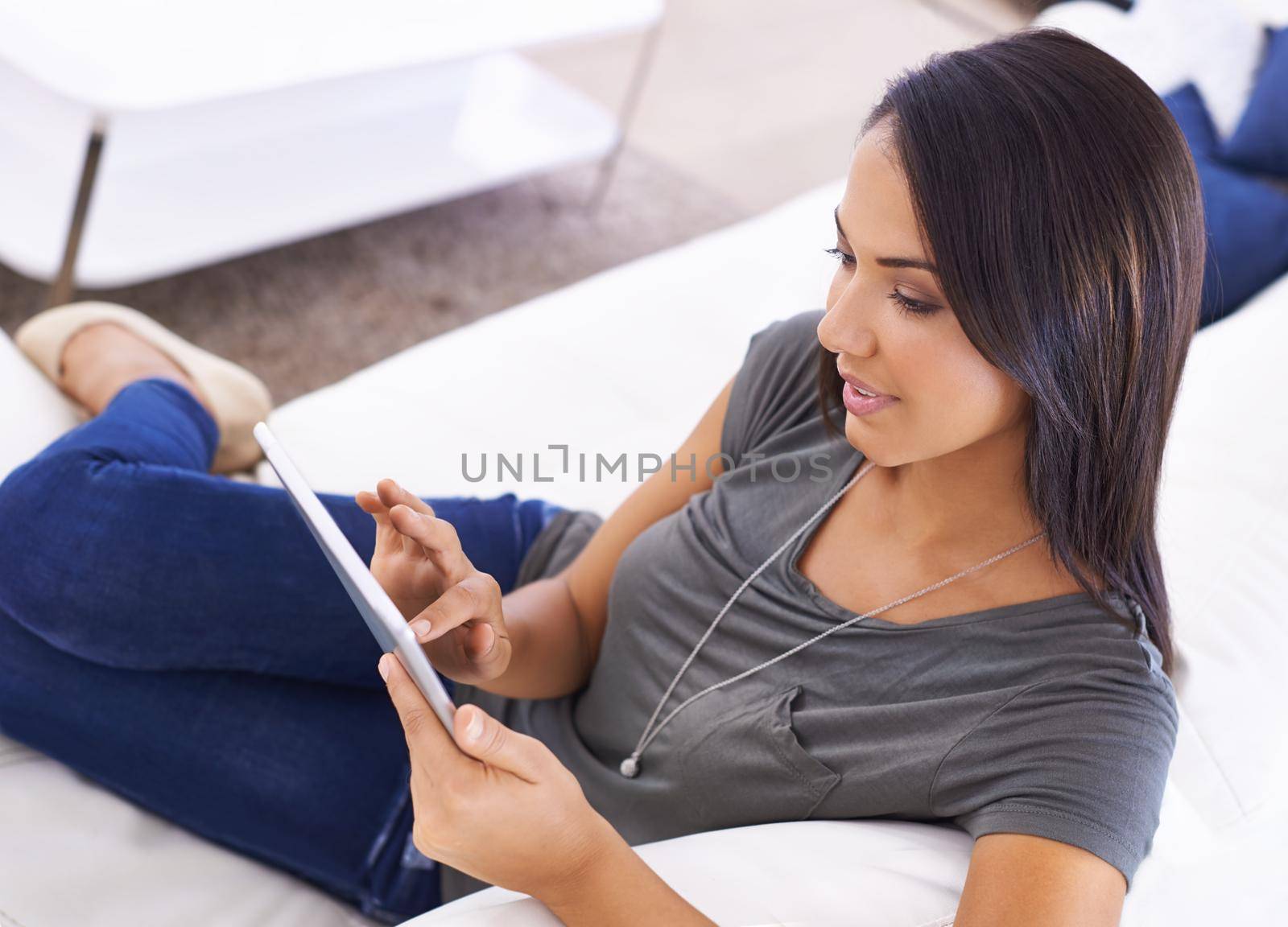 Communication made conventient. an attractive young woman using her digital tablet at home