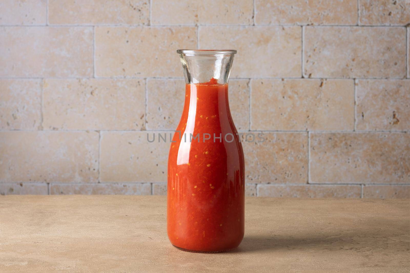 A glass jar bottle with homemade tomato sauce stands on the table. Selective focus.