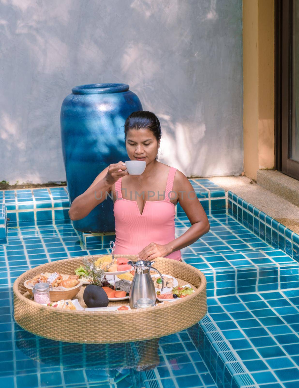 women having breakfast in swimming pool , Asian women having floating breakfast by fokkebok