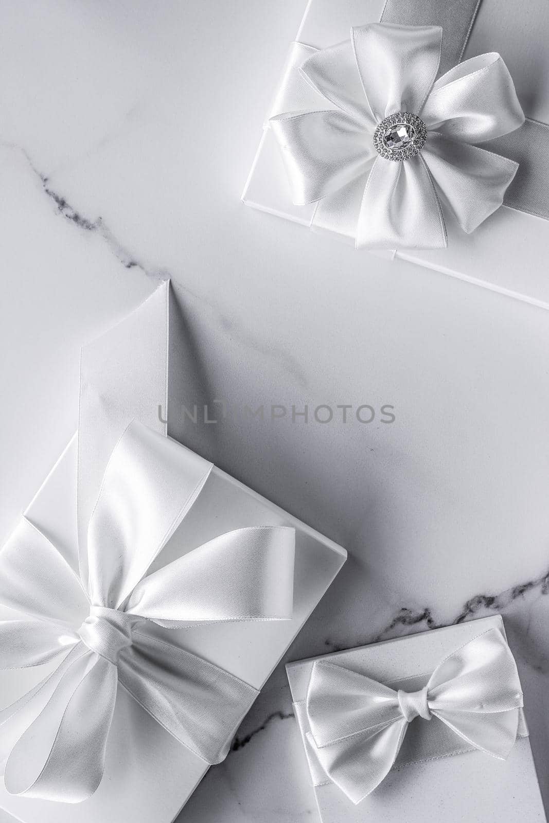 Romantic celebration, bridal decor and holiday present concept - Luxury wedding gifts with silk bow and ribbons on marble background