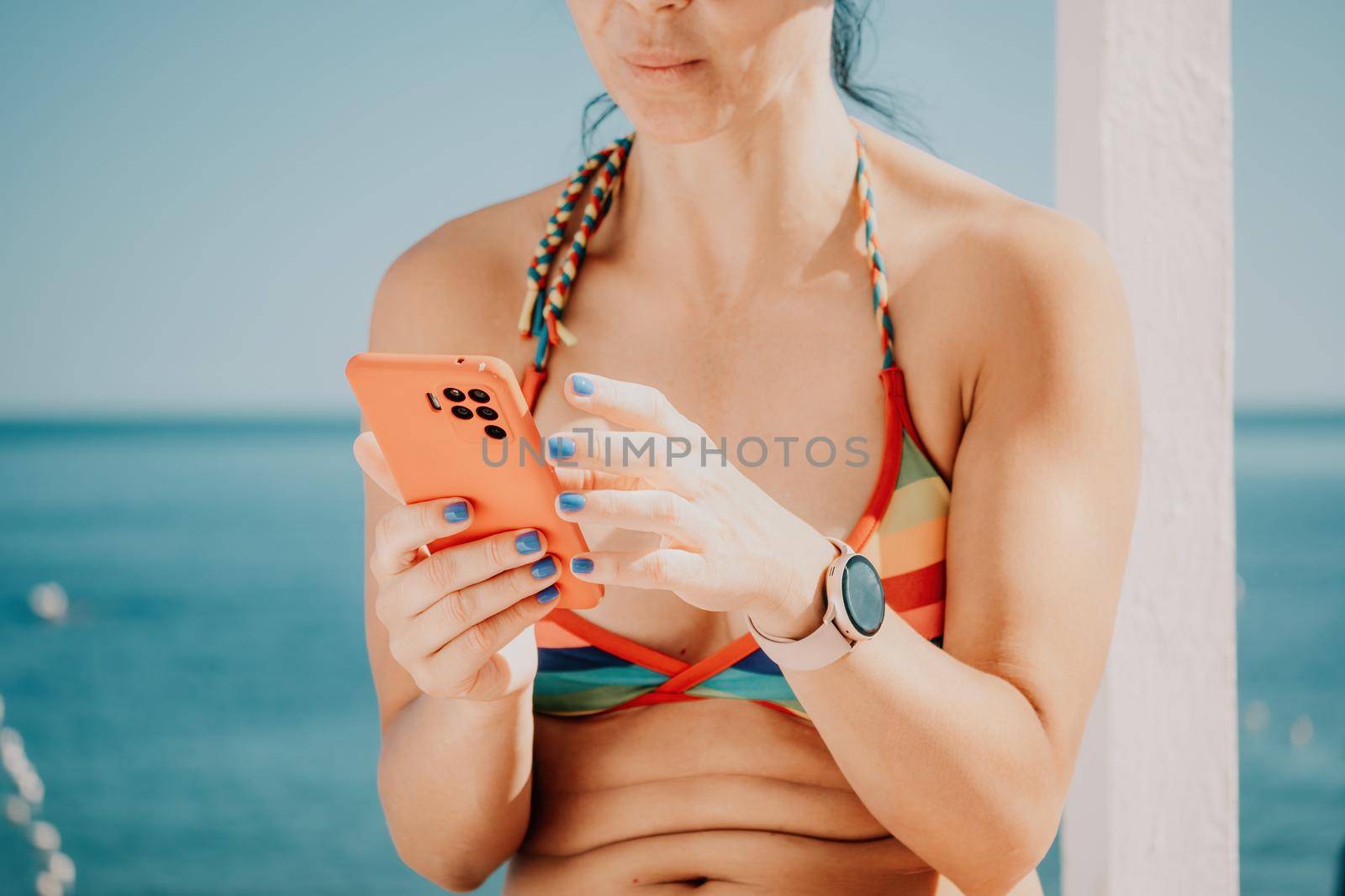 Woman in rainbow bikini. Happy tanned girl in rainbow swimsuit at seaside, blue sea water in background