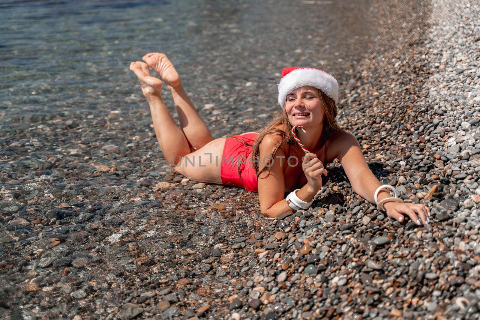 Portrait of attractive girl in red santa hat celebrating christmas holidays at sea, exotic travel and vacation concept.