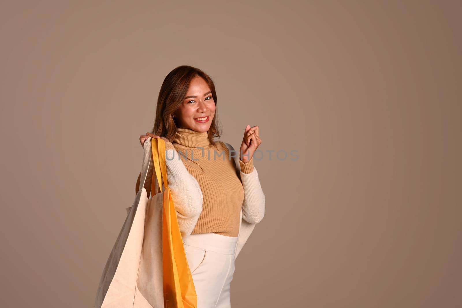 Beautiful fashionable woman in autumn outfit posing on beige background. Fashion studio photo, Autumn fashion and beauty concept.