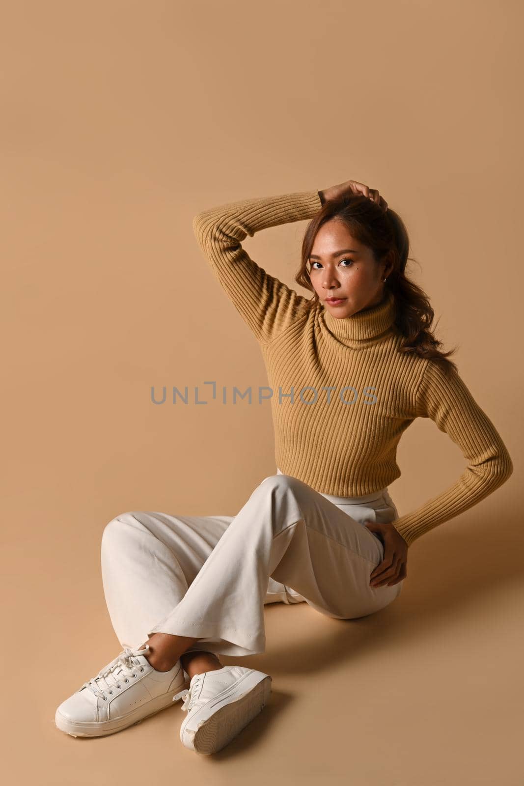Beautiful fashionable woman in autumn outfit posing on beige background. Fashion studio photo, Autumn fashion and beauty concept by prathanchorruangsak