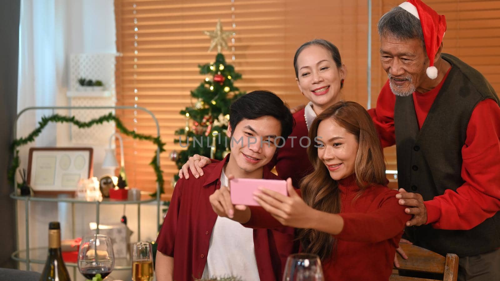 Image of happy family celebrating Christmas together at home lighted with soft lights and candles. Celebration, holidays and people concept.