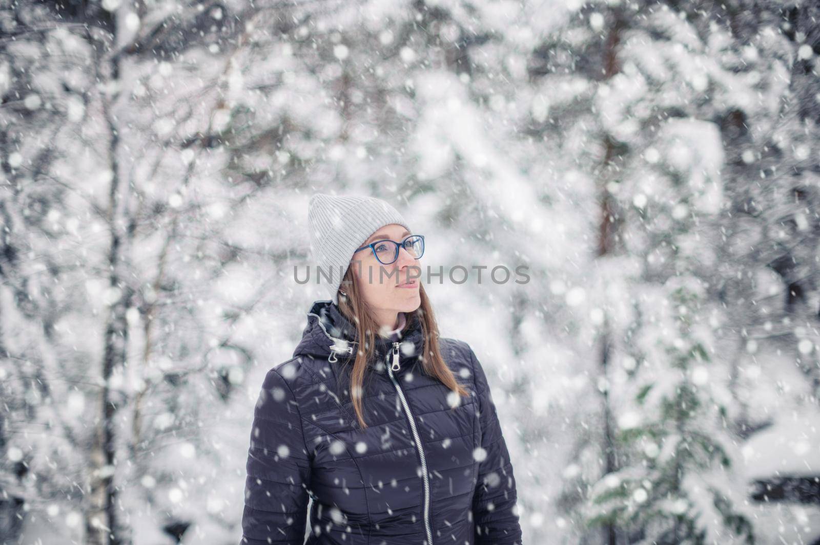 Woman in winter jacket walking in snowy winter forest, snowy winter day