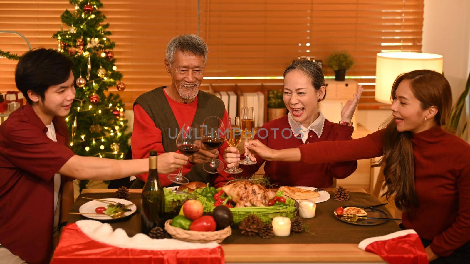 Image of happy family celebrating Christmas together at home lighted with soft lights and candles. Celebration, holidays and people concept.