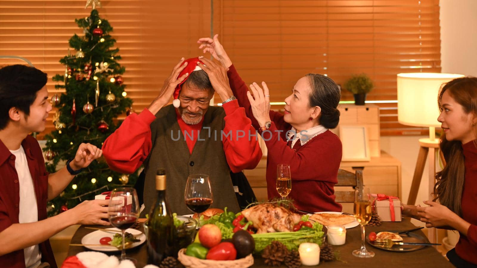 Image of happy family celebrating Christmas together at home lighted with soft lights and candles. Celebration, holidays and people concept by prathanchorruangsak