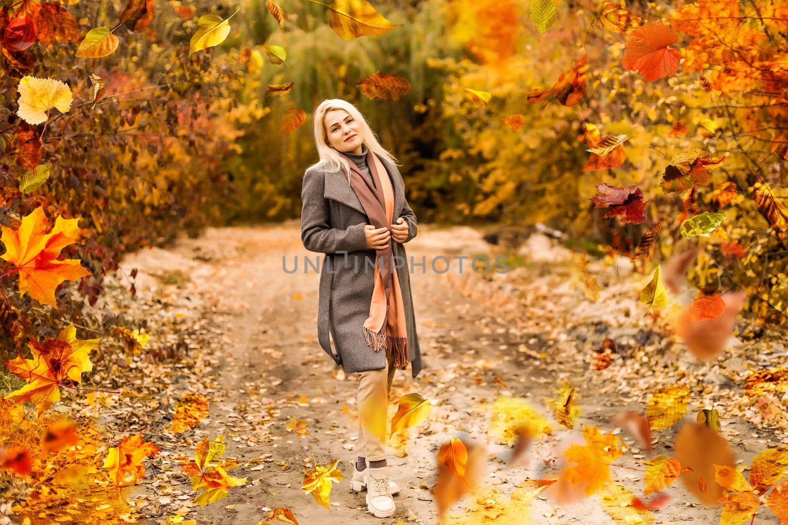 Beautiful girl walking outdoors in autumn. Smiling girl collects yellow leaves in autumn. Young woman enjoying autumn weather. High quality photo