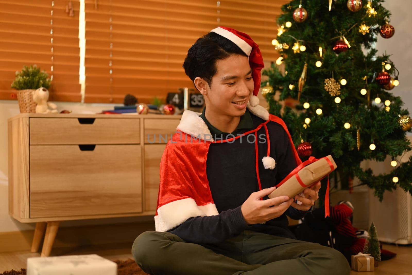 Happy emotional man with Christmas gifts and sitting in decorated room for celebrating New year and Christmas festive.