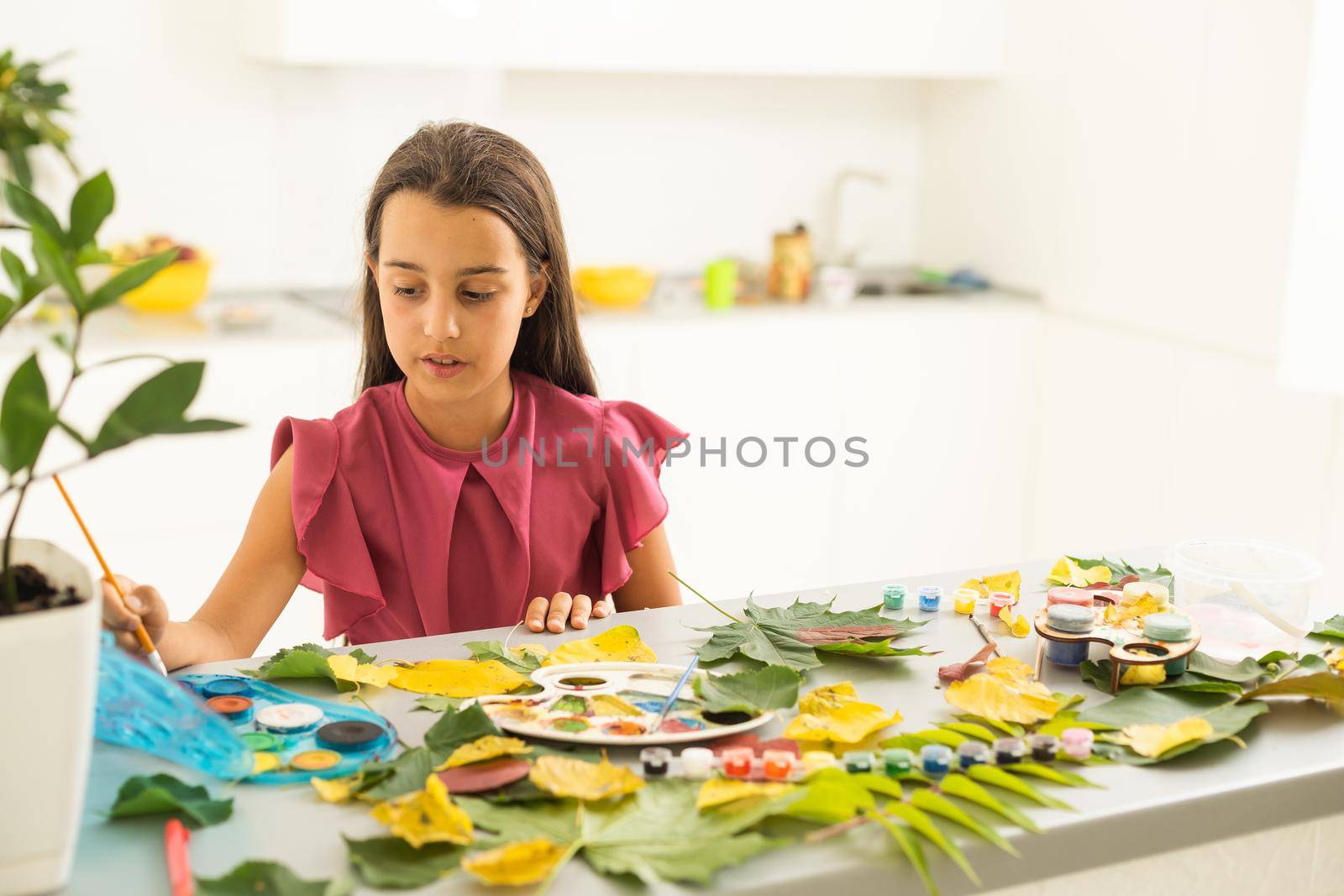little girl artist paints autumn leaves . High quality photo