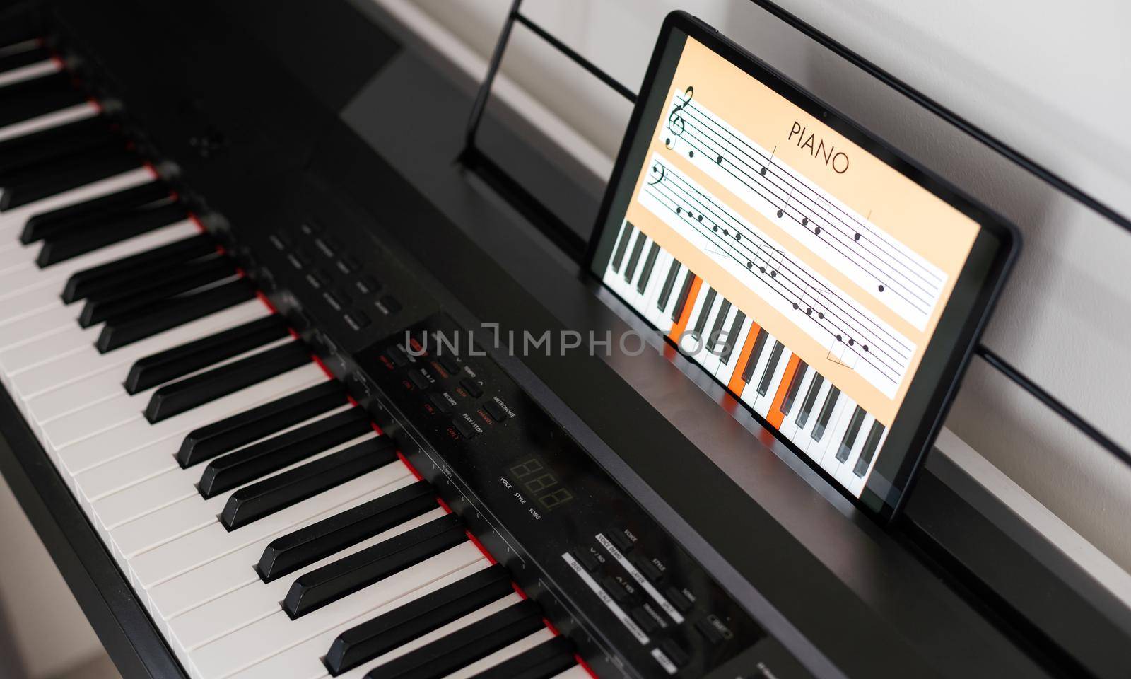 Piano keys, music notebook and tablet on the background of the wall. Mock up for online piano courses