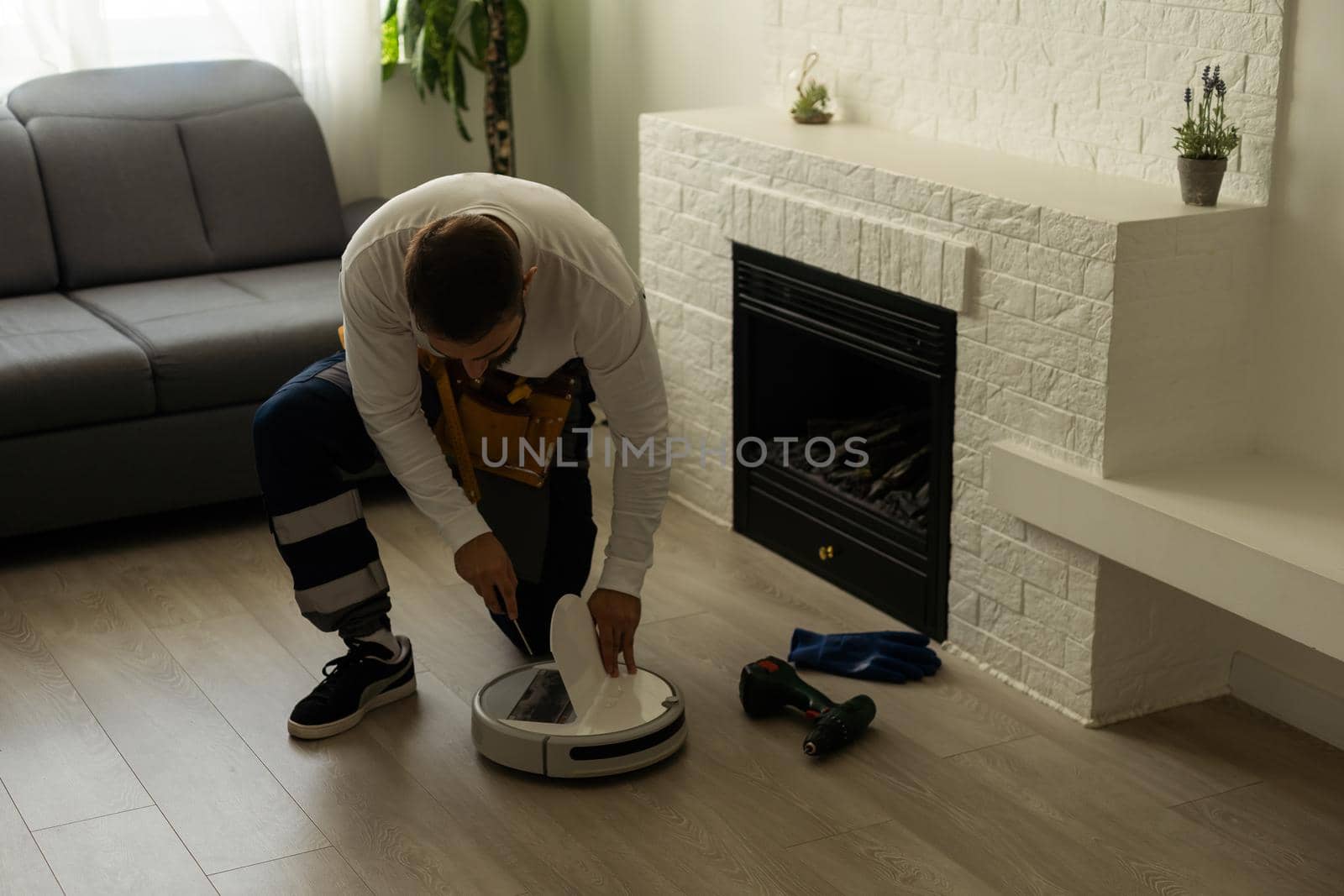 Housework and technology concept. Maintenance and service of robot vacuum cleaner. Cleaning, repair, replacement of parts. Man repairing robot cleaner at home. Smart home functions, fully automated.