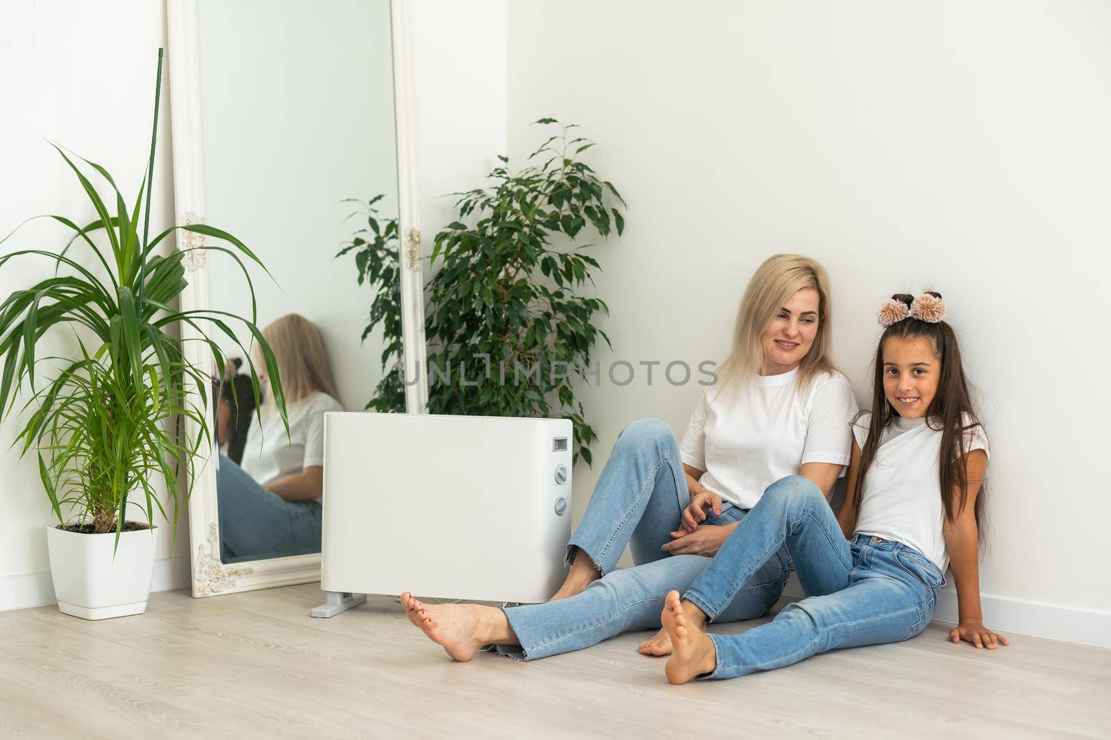 Electric heater at home. Young family warms near a heating radiator