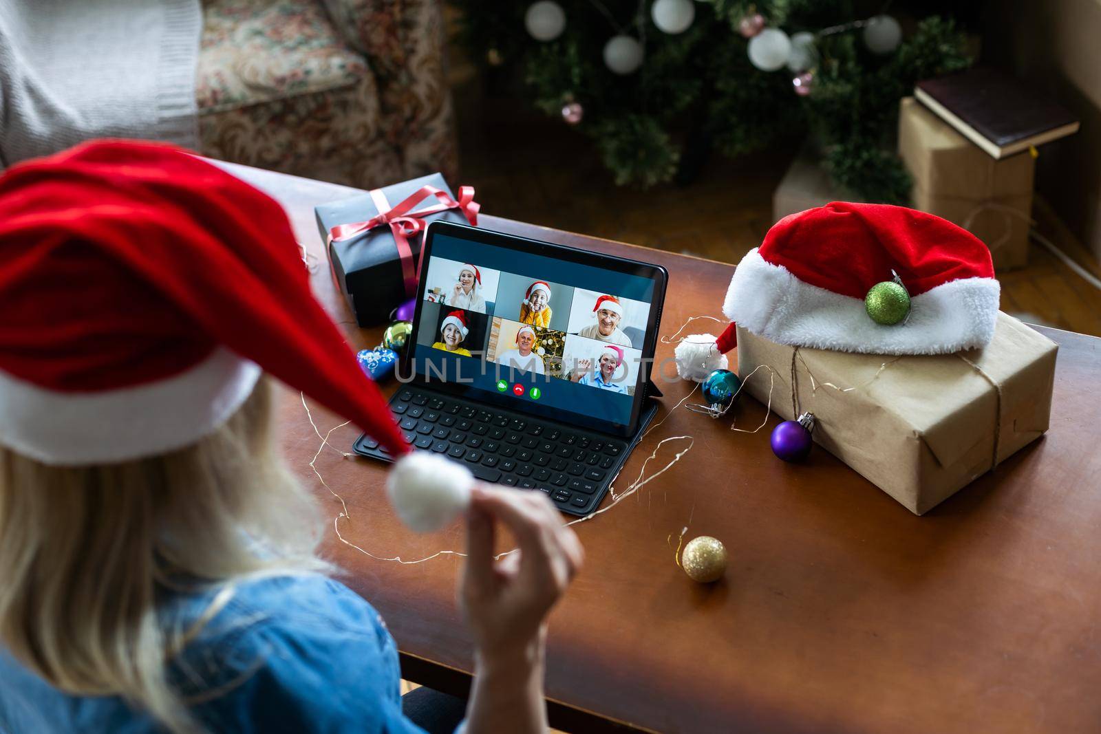 A middle-aged blonde woman uses a tablet for a video call while sitting in an armchair by Andelov13