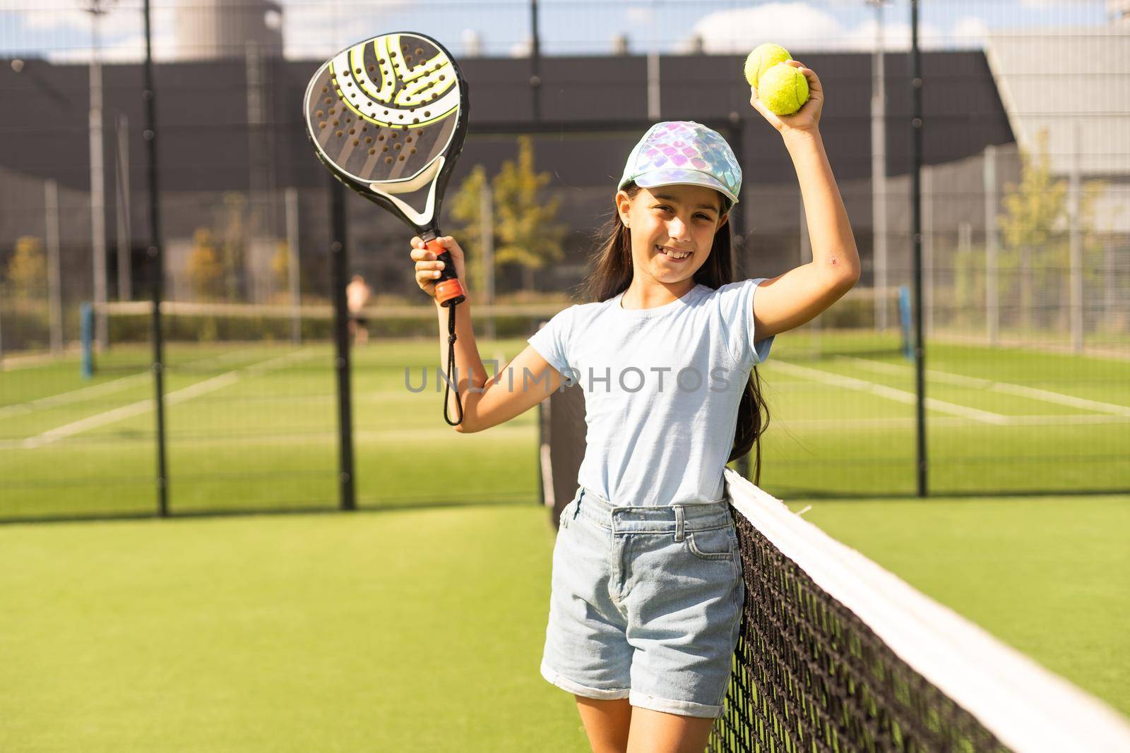 little girl with racket playing padel tennis at court.