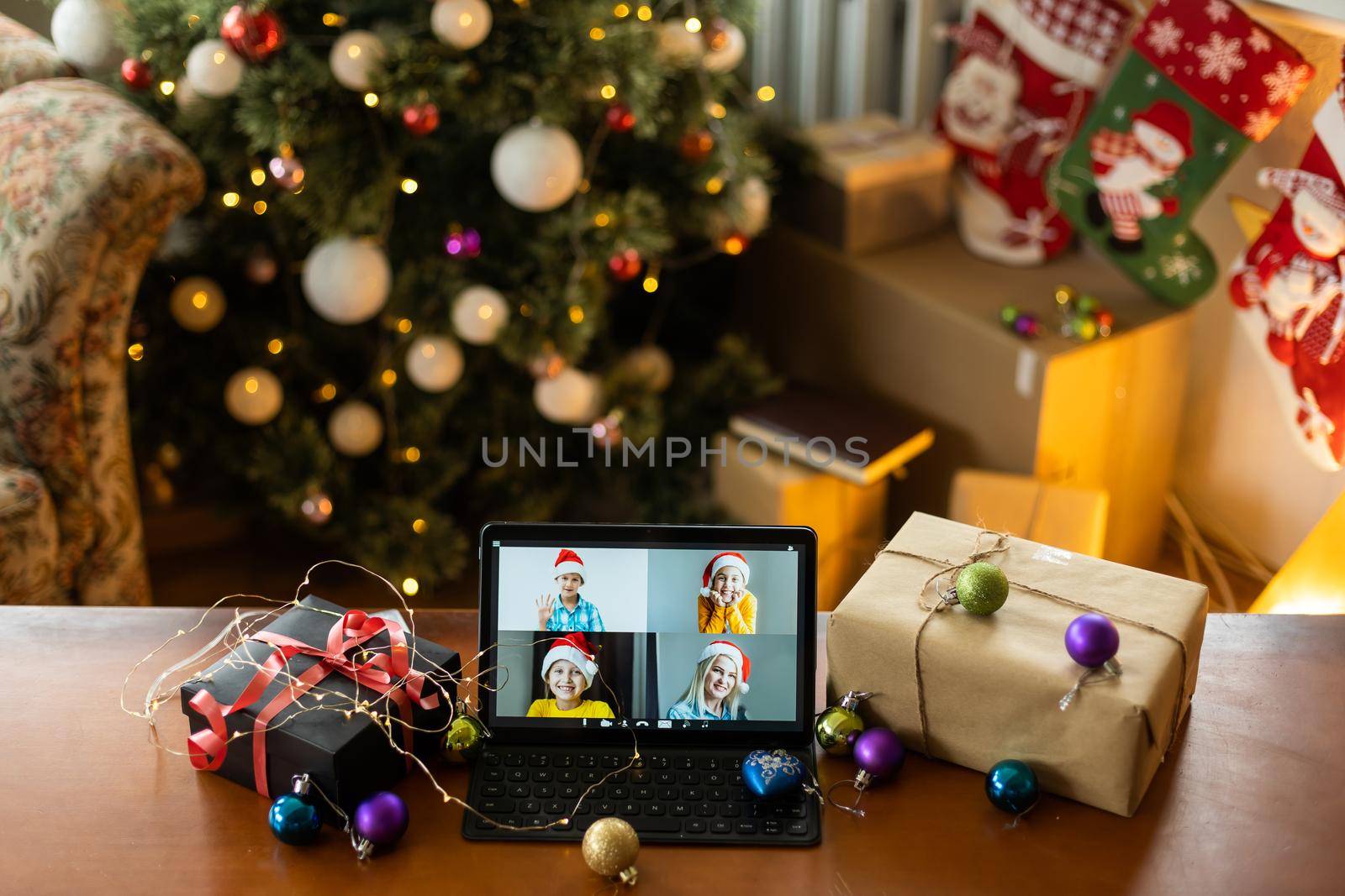 Family video call with kid presenting gift by remote chat digital tablet screen on Merry Christmas table holiday background. Xmas online virtual family party celebration, Happy New Year videocall.
