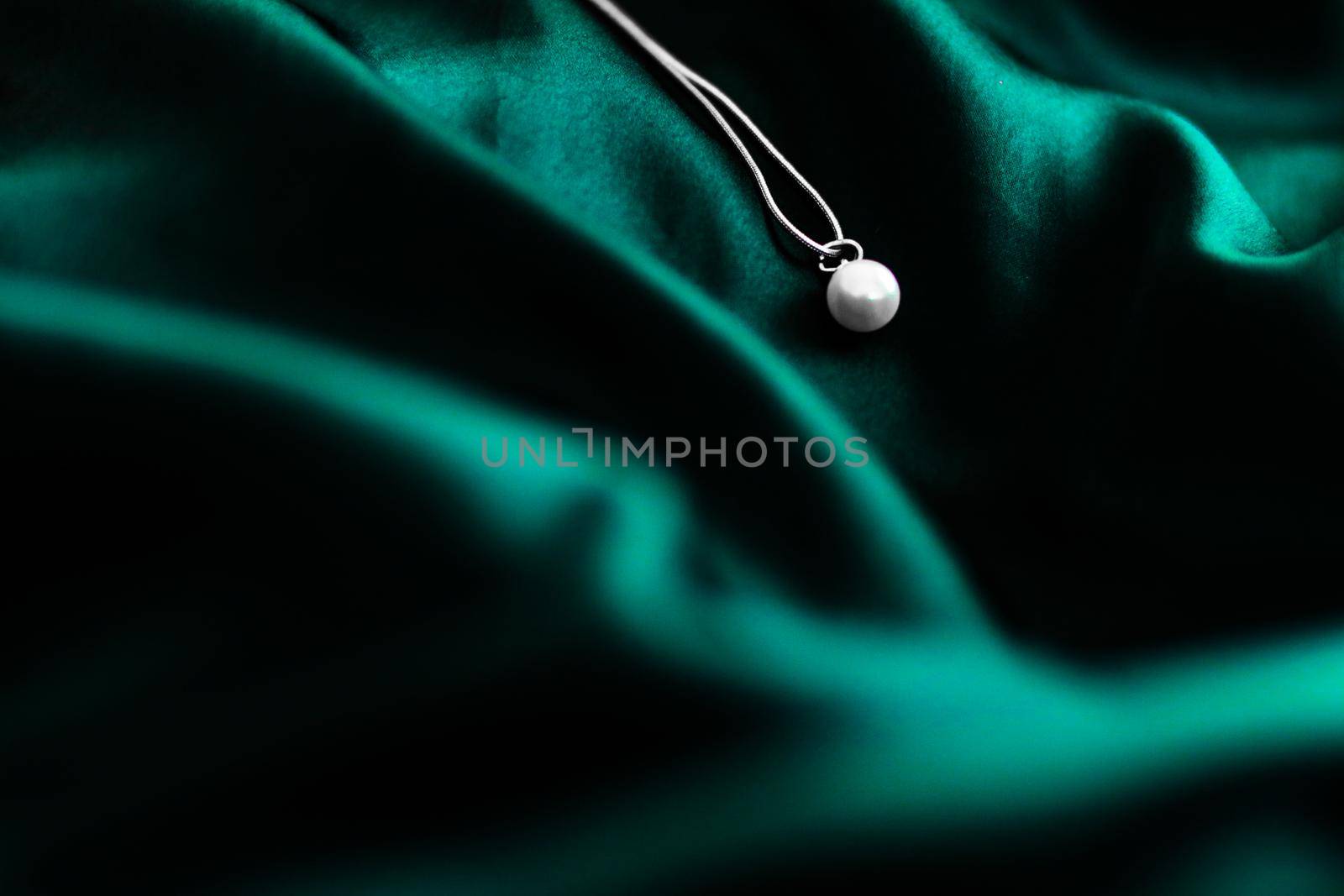 Luxury white gold pearl necklace on dark emerald green silk background, holiday glamour jewelery present by Anneleven