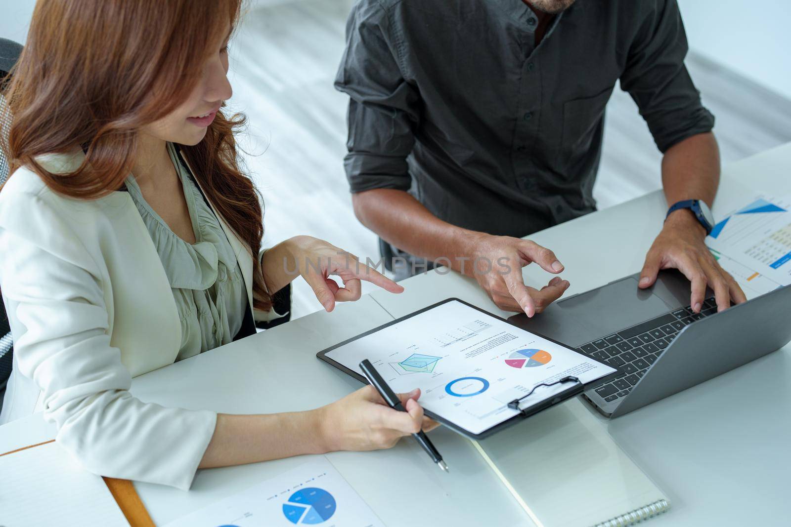A portrait of a female marketer and a male salesperson discussing how to increase sales by investing in new products to expand marketing using documents and computers in working, new idea product.
