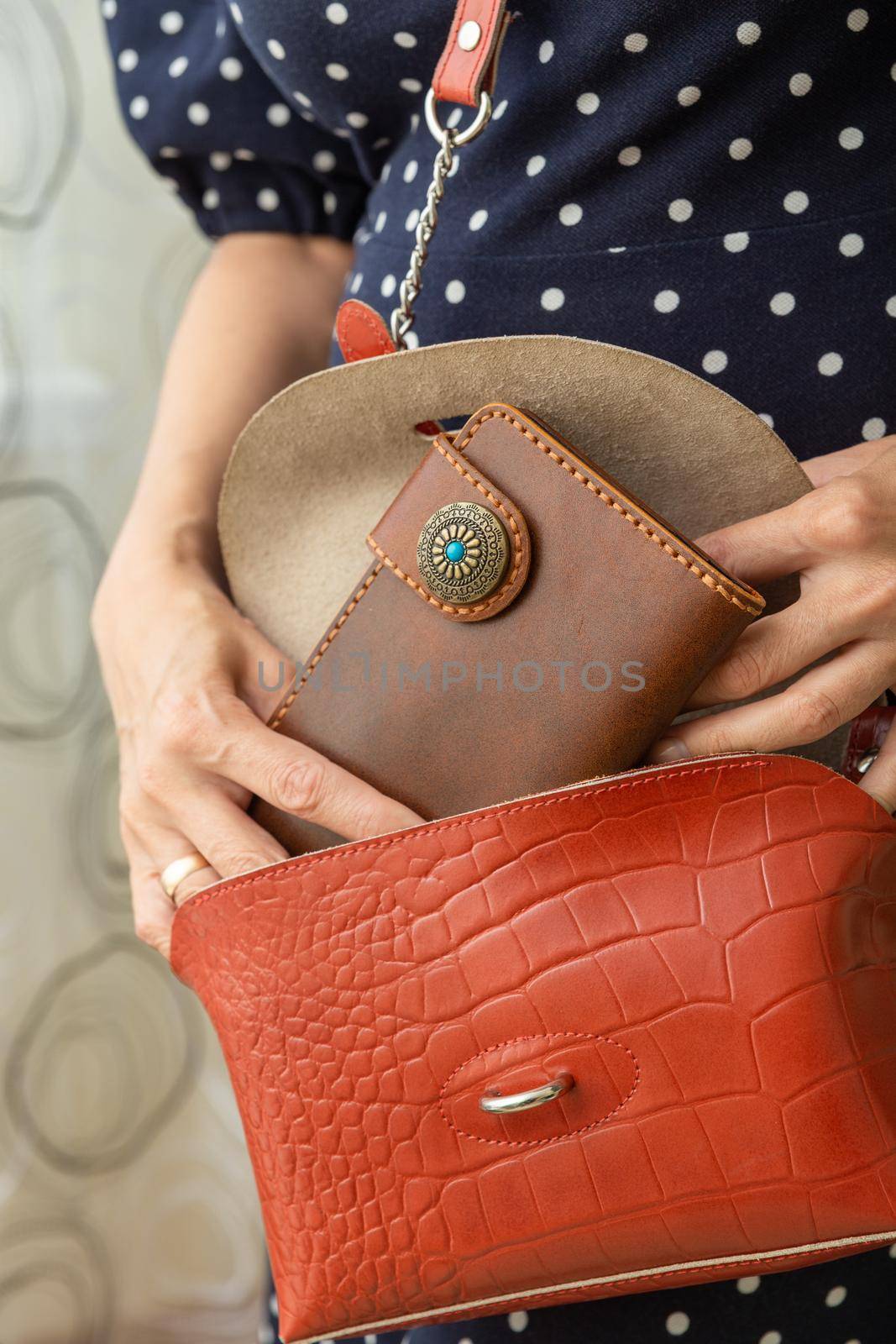 Woman takes a brown natural leather wallet out of her purse. Wallet made of genuine leather, a beautiful and practical women's accessory.