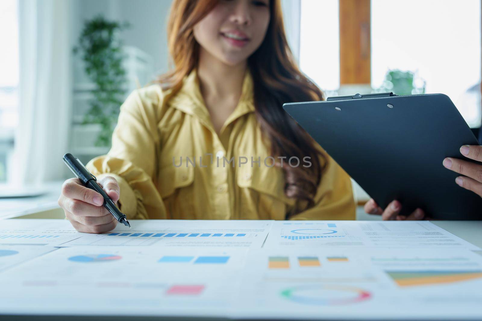 A portrait of a female business owner consulting a male salesperson to devise a strategy to increase revenue from new incoming goods using investment budget documents and an analytical computer.