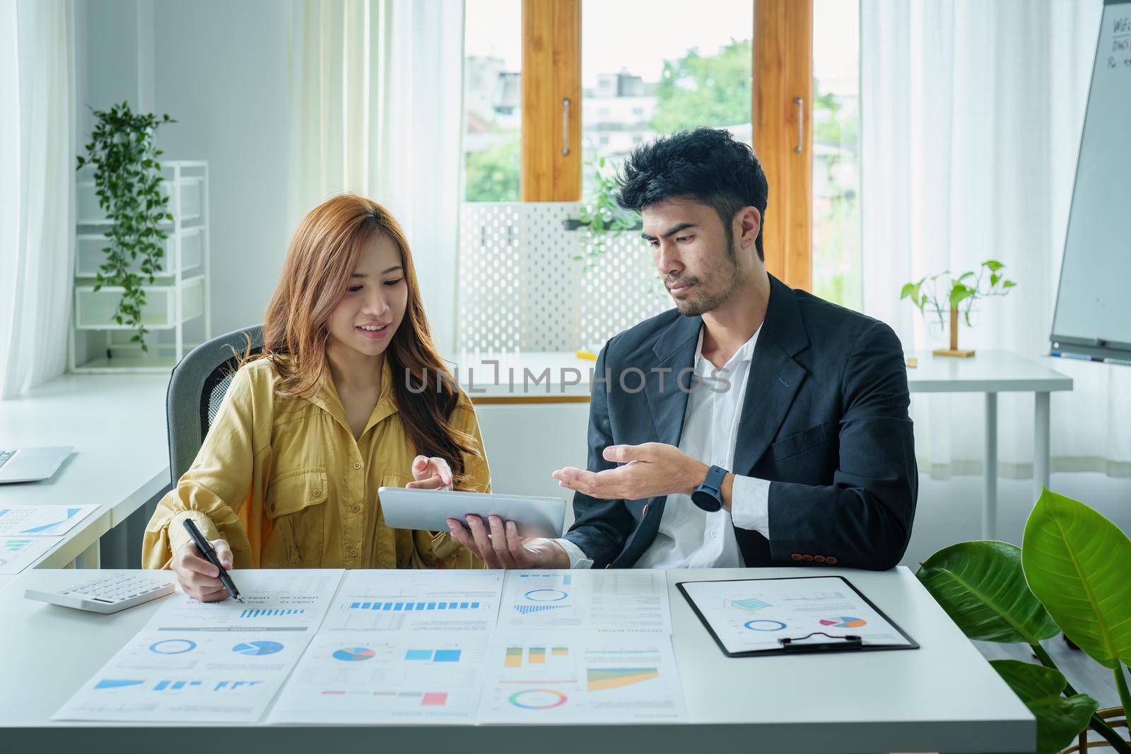 A portrait of a female business owner consulting a male salesperson to devise a strategy to increase revenue from new incoming goods using investment budget documents and an analytical computer.