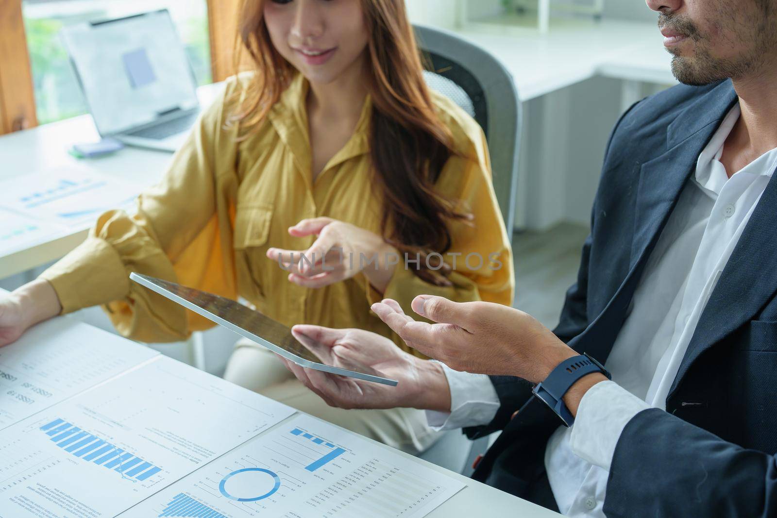 A portrait of a female business owner consulting a male salesperson to devise a strategy to increase revenue from new incoming goods using investment budget documents and an analytical computer.