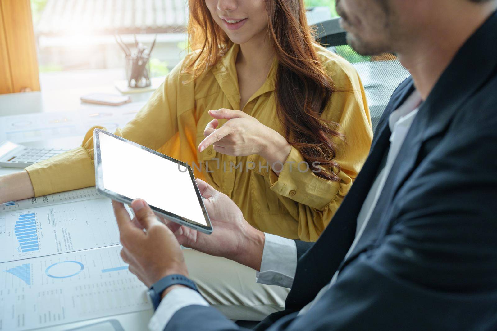 A portrait of a female business owner consulting a male salesperson to devise a strategy to increase revenue from new incoming goods using investment budget documents and an analytical computer.