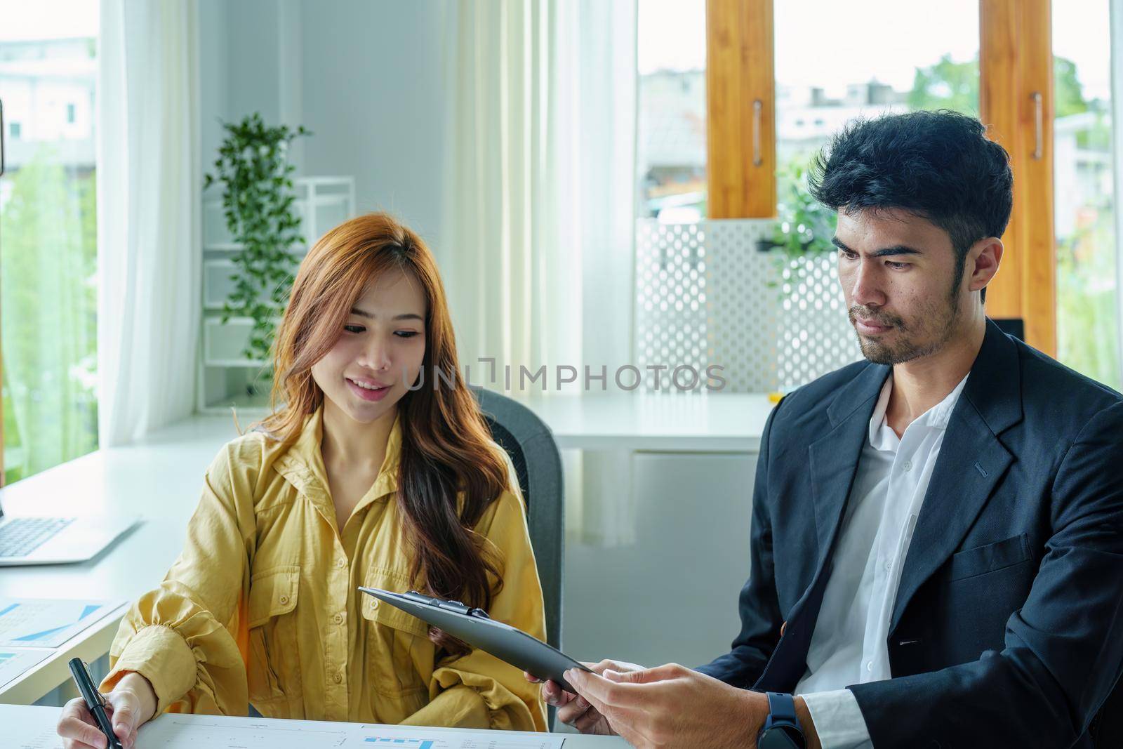 A portrait of a female business owner consulting a male salesperson to devise a strategy to increase revenue from new incoming goods using investment budget documents and an analytical computer.