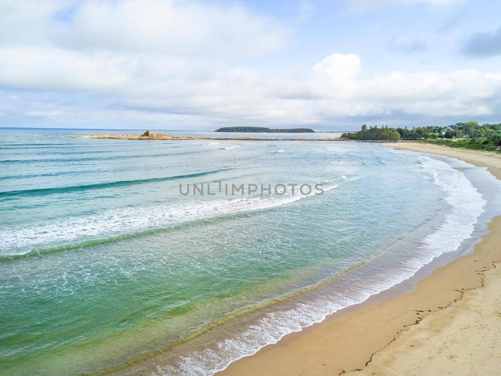 Scenic beach views to Mossy Point Australia with pretty sky with soft fluffy clouds and gentle waves lap the shore