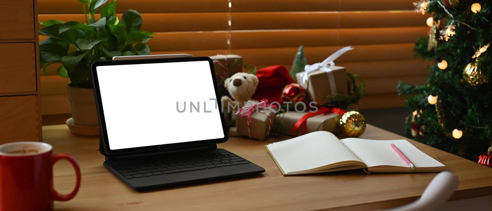 Mock up computer notebook, coffee cup and Christmas gifts on wooden table.