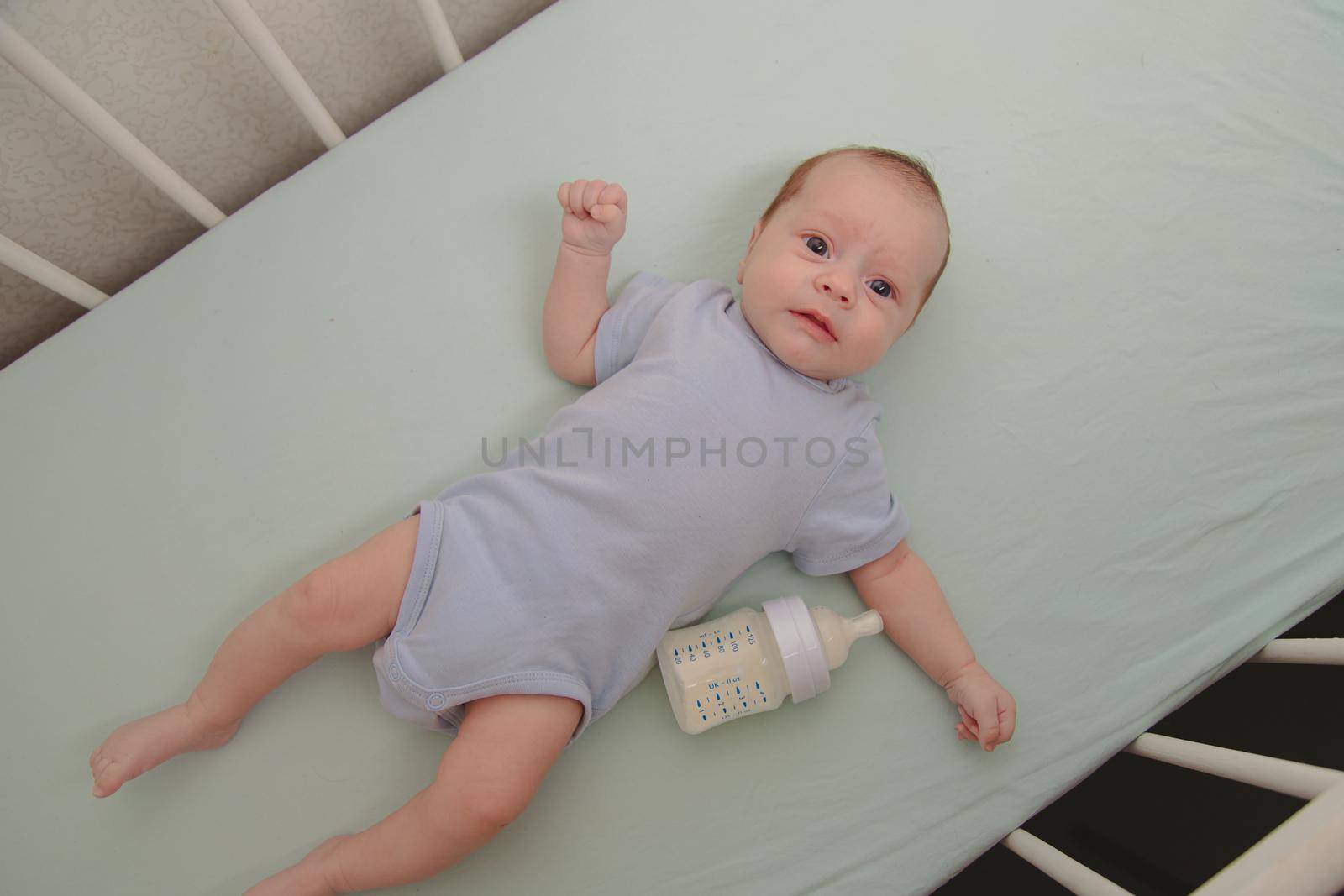 Baby with a bottle in the crib top view . Baby food copyspace . Children's food. Hungry baby. by alenka2194