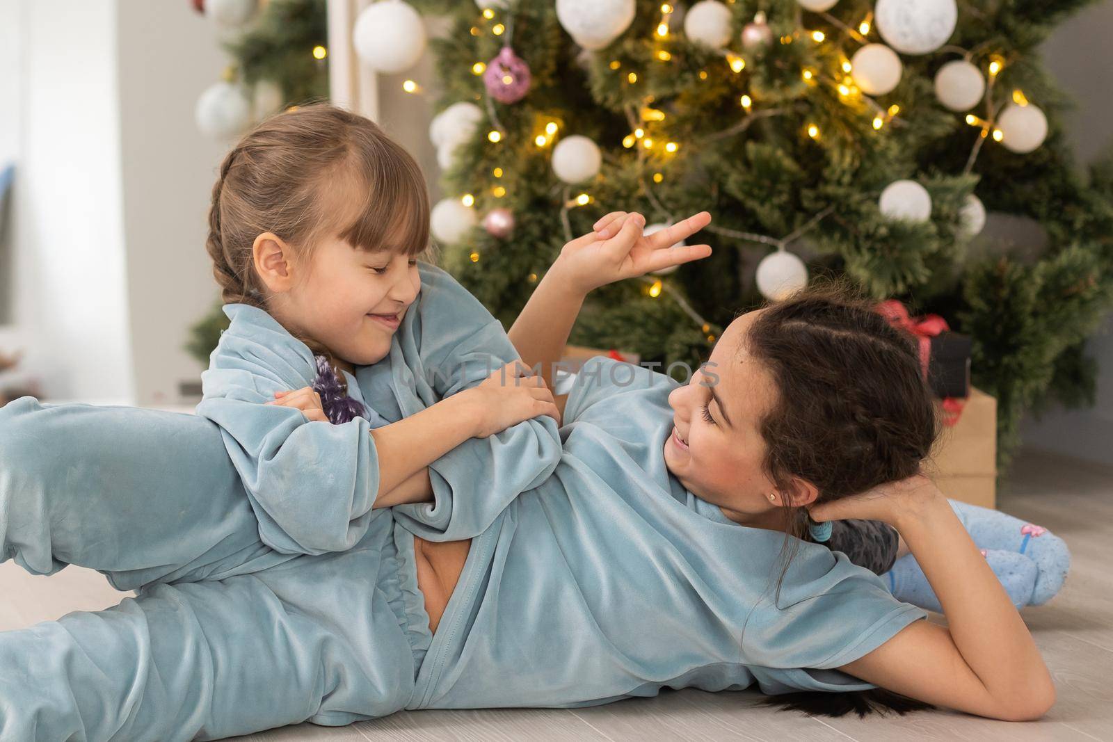 Two cute beautiful girls near the Christmas tree with gifts. New Year. Christmas.