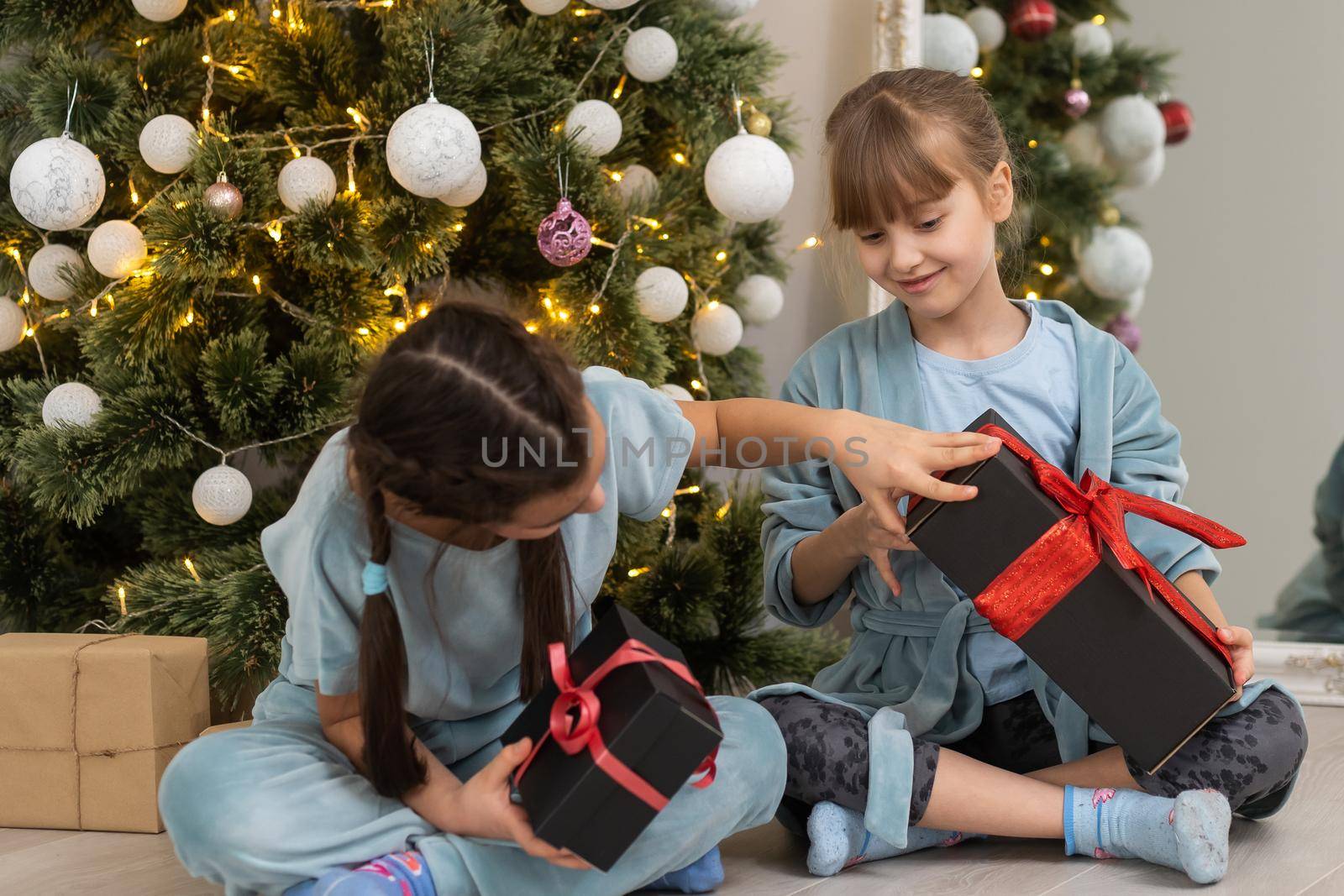 two little girls with presents around the Christmas tree