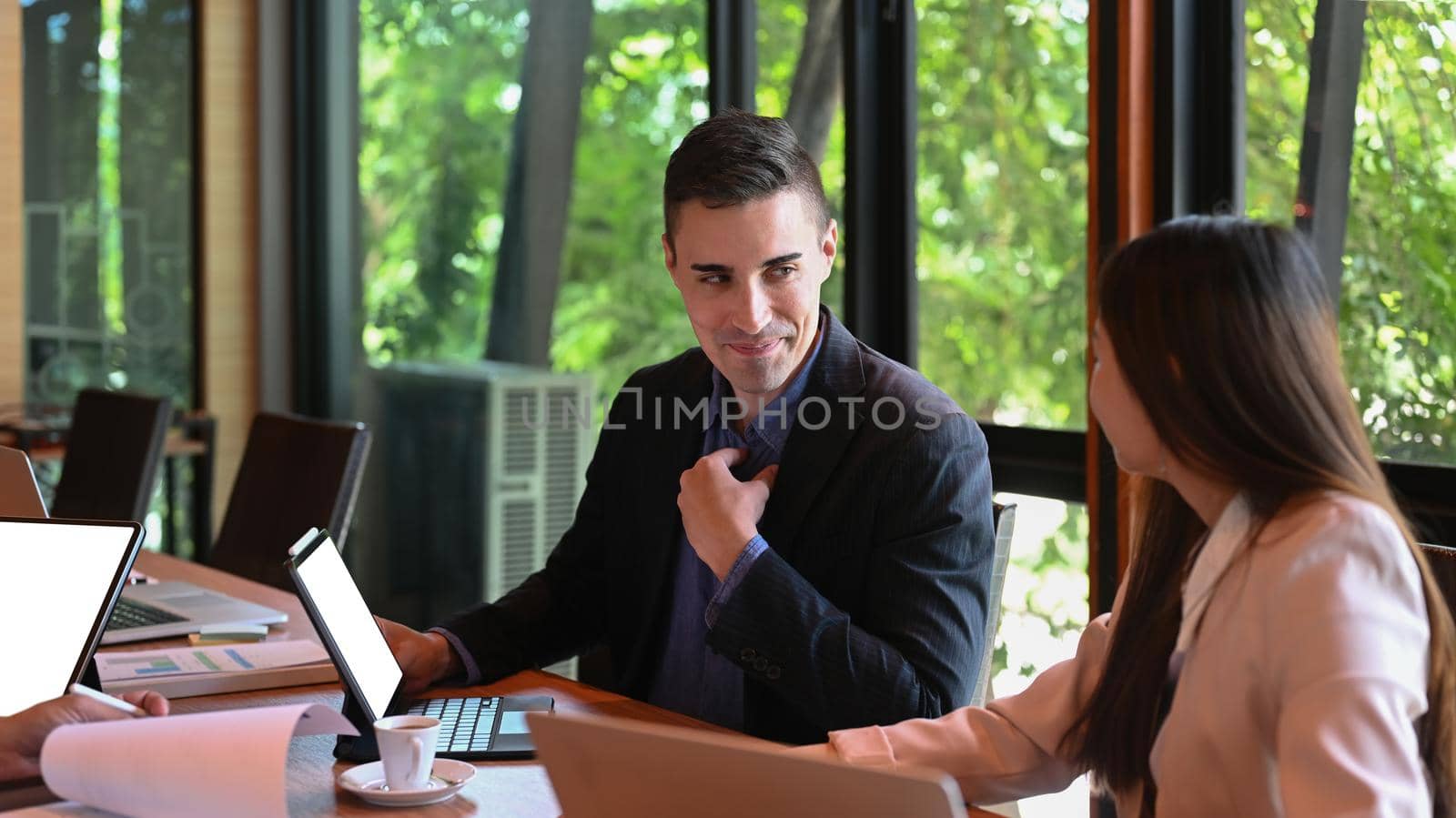 Handsome man business leader explaining some information to his colleagues. by prathanchorruangsak