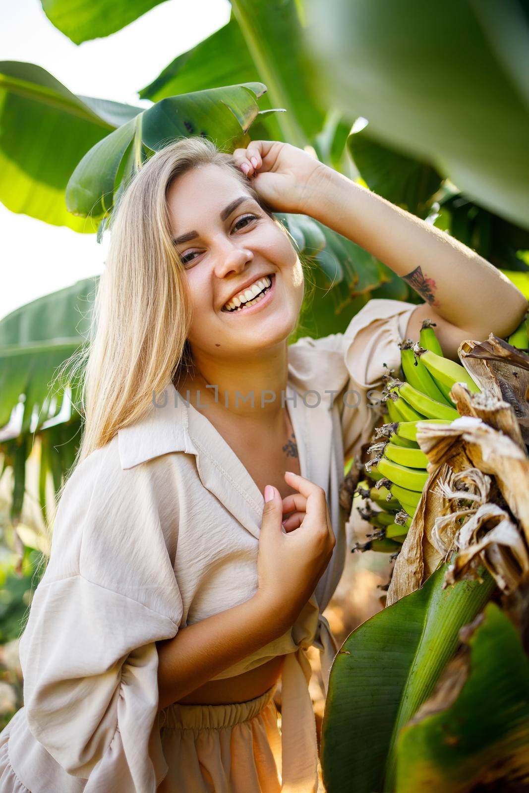 Woman near large green leaf of banana tree on nature in park. Tropical plants by Dmitrytph