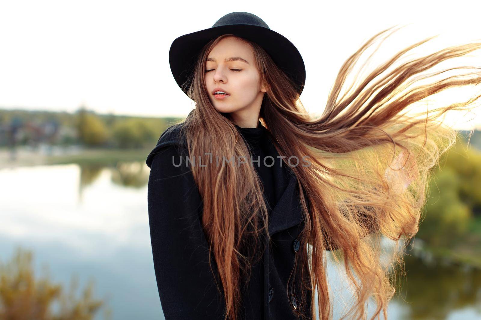 Close-up portrait of young beautiful fashionable woman in black hat, with long hair. Female fashion, beauty concept. Outdoor.