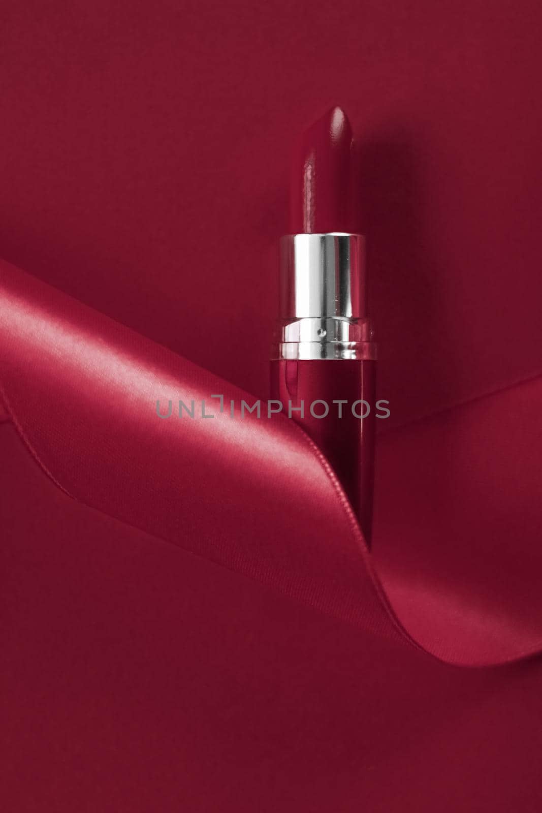 Luxury lipstick and silk ribbon on maroon holiday background, make-up and cosmetics flatlay for beauty brand product design by Anneleven