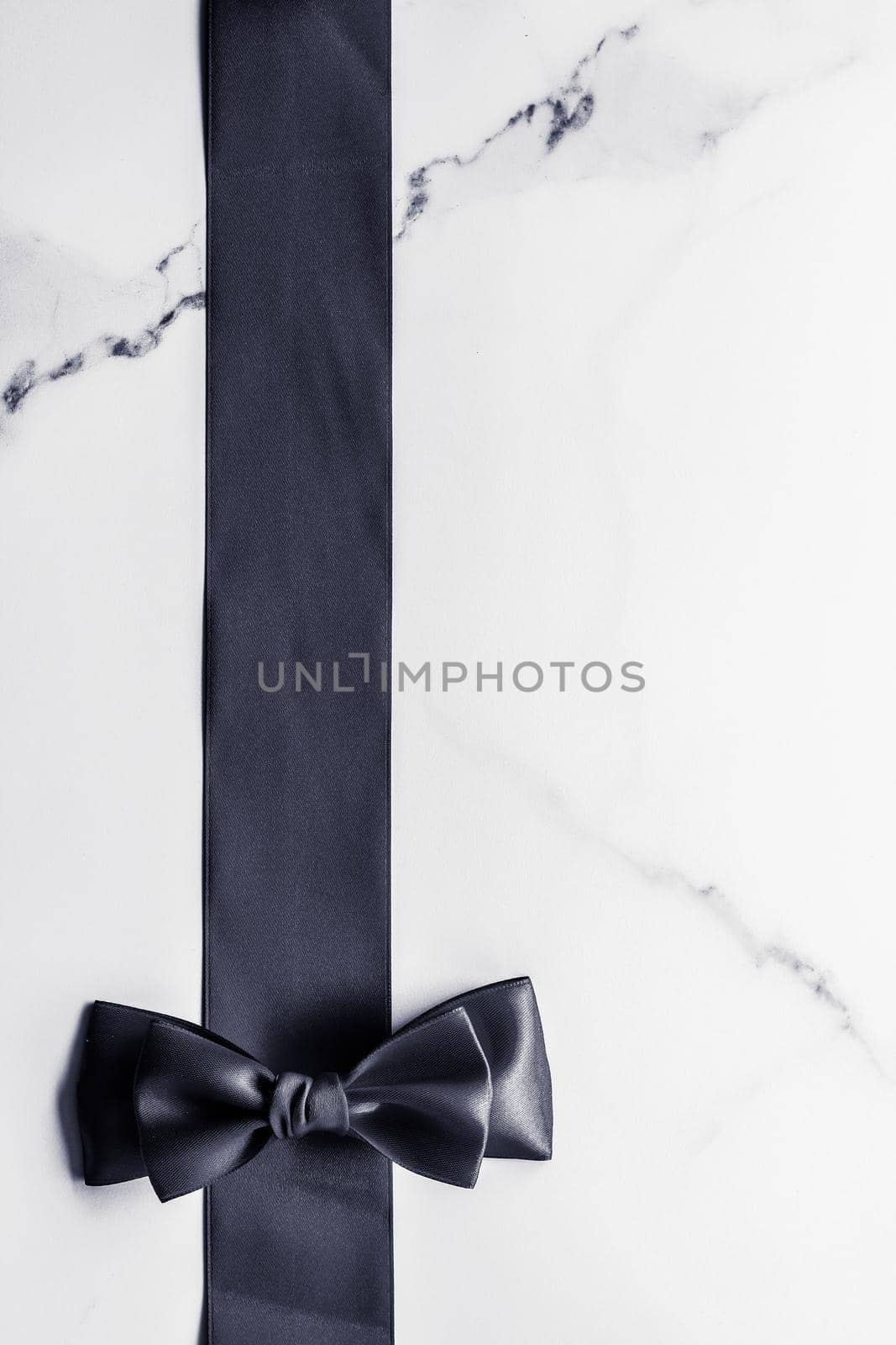 Holiday gift, decoration and sale promotion concept - Black silk ribbon and bow on marble background, flatlay