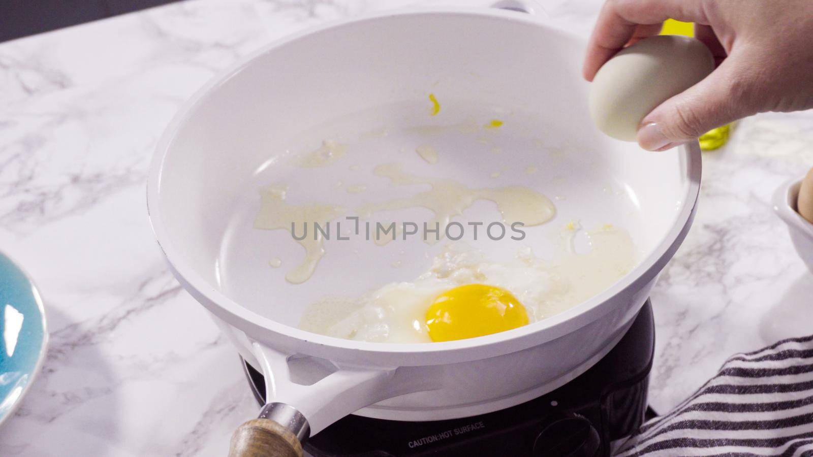 Frying farm fresh eggs in a white skillet.