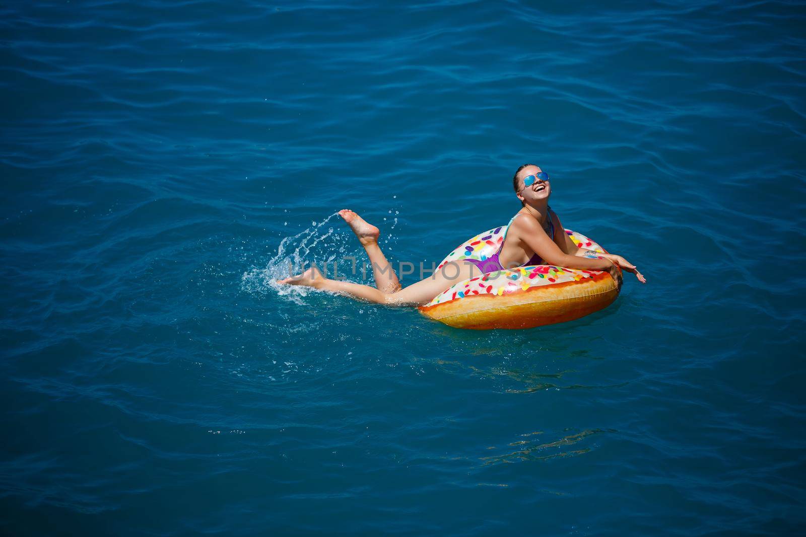 Carefree young girl woman enjoying a relaxing day at sea, floating on an inflatable ring, top view. Sea vacation concept