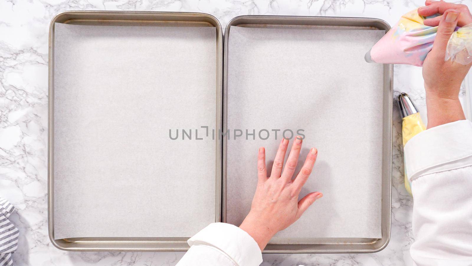 Step by step. Flat lay. Piping unicorn meringue cookies to the baking sheet lined with a parchment paper.