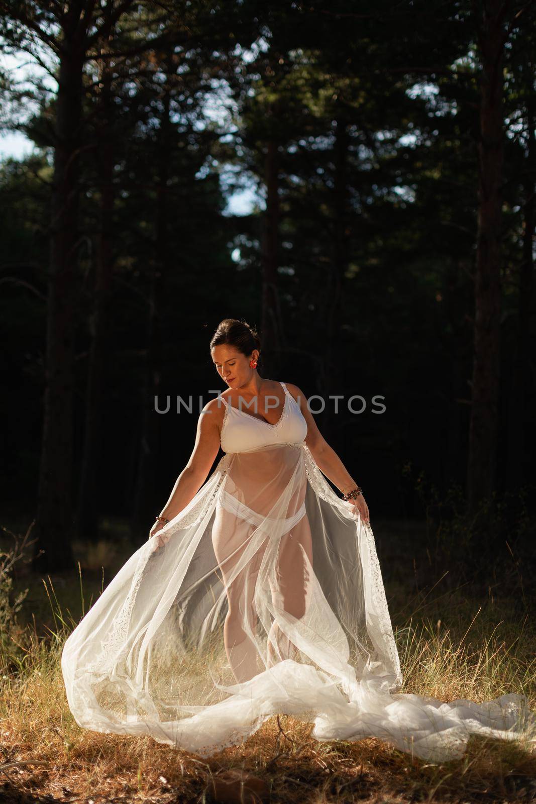 A pregnant woman poses holding part of her wedding dress with her hands by stockrojoverdeyazul
