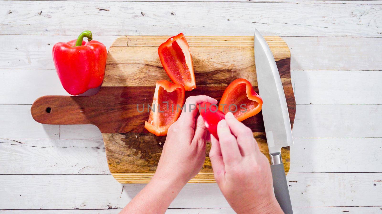 Flat lay. Mincing organic red bell peppers on a wood cutting board.