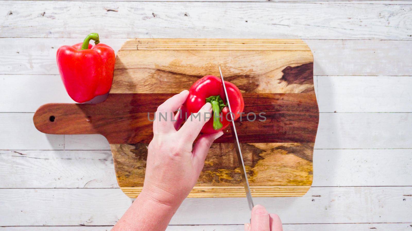 Flat lay. Mincing organic red bell peppers on a wood cutting board.