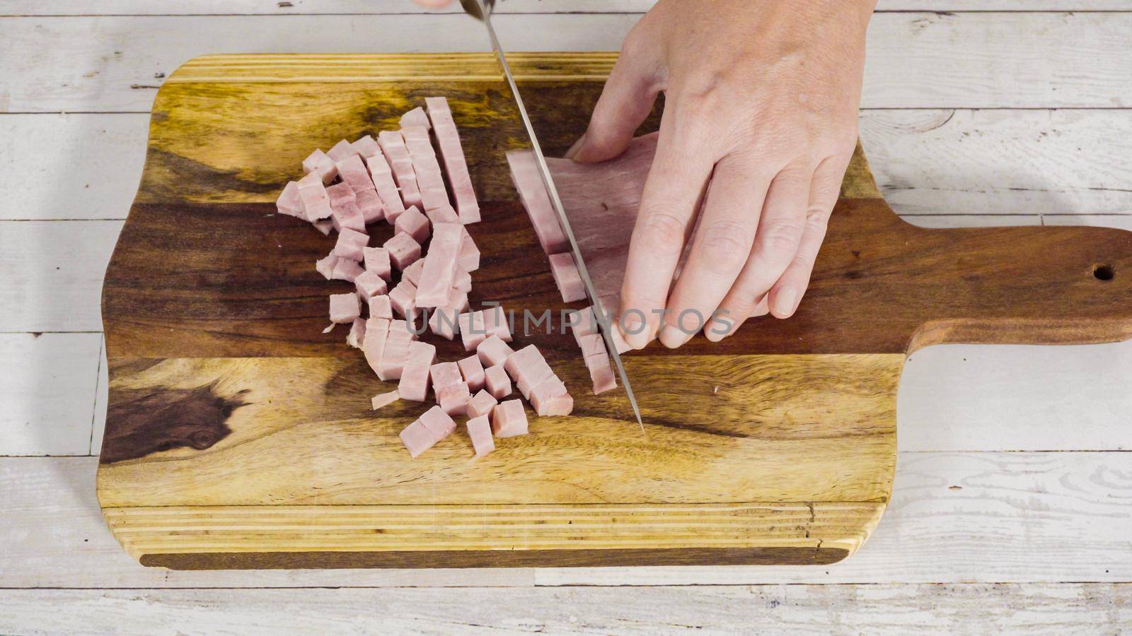 Cutting organic honey ham on a wood cutting board.