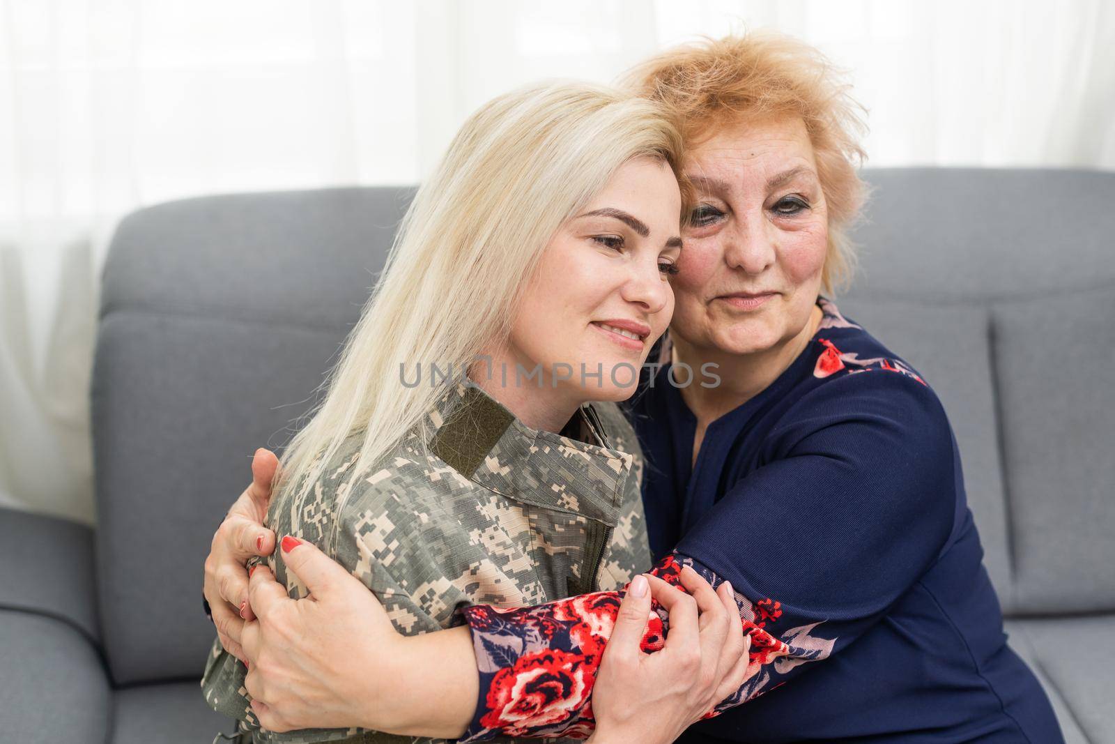 Soldier woman returning home to her family, embracing his mother, close up.