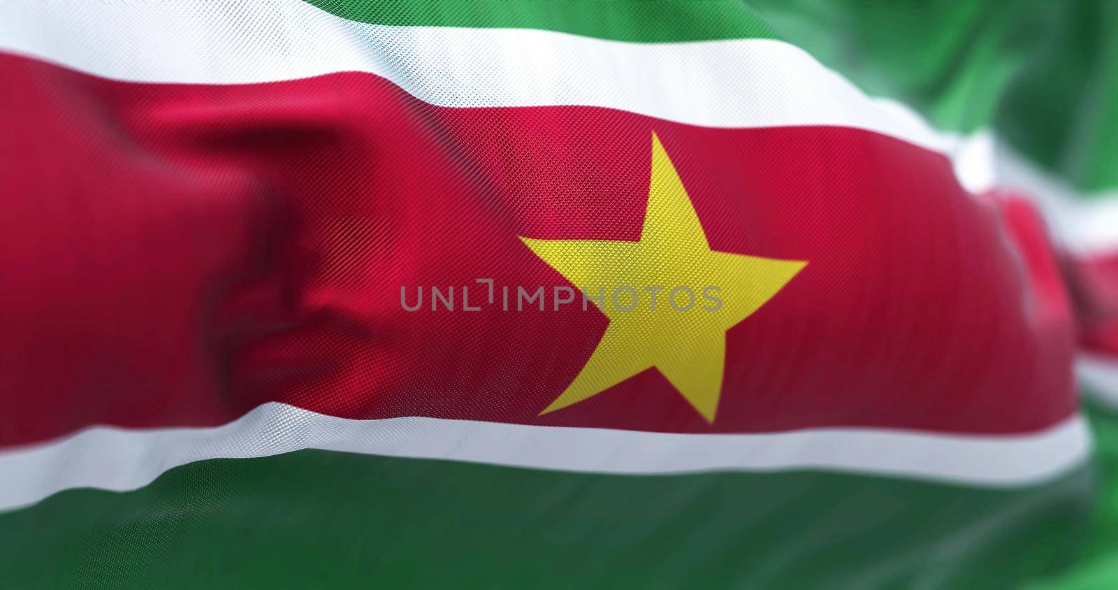 Close-up view of Suriname national flag waving in the wind. The Republic of Suriname is a country on the northeastern Atlantic coast of South America. Fabric textured background. Selective focus